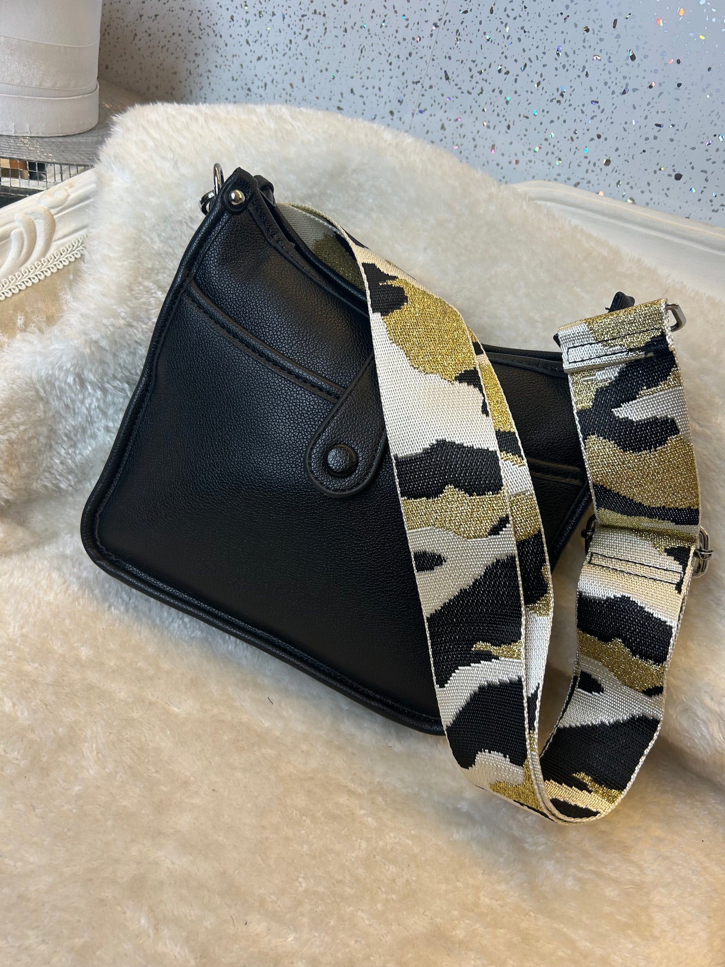 Black bag with a patterned strap on a textured surface