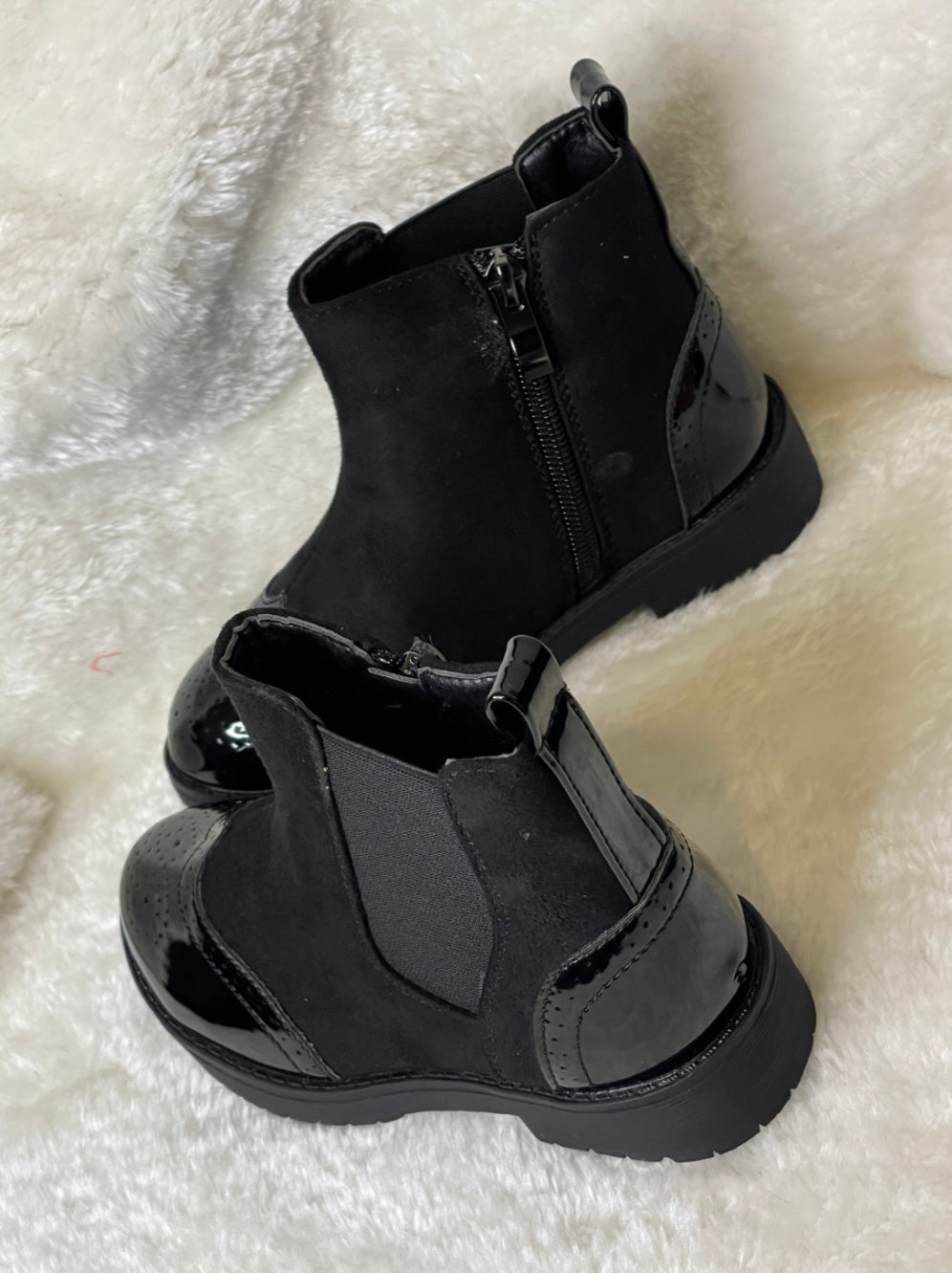 A pair of black ankle boots for girls with a glossy finish