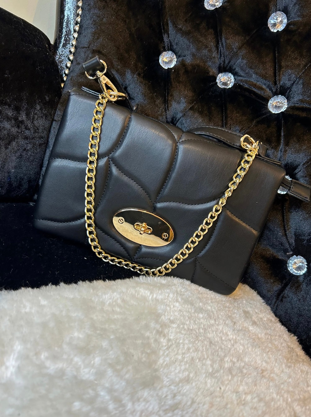 Black quilted handbag with a gold chain strap