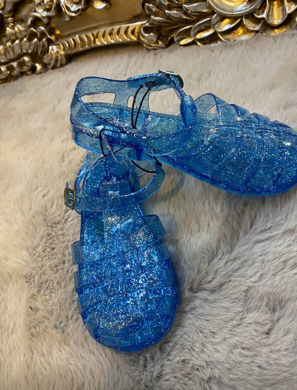 A pair of blue jelly-textured children's shoes with a glittery finish