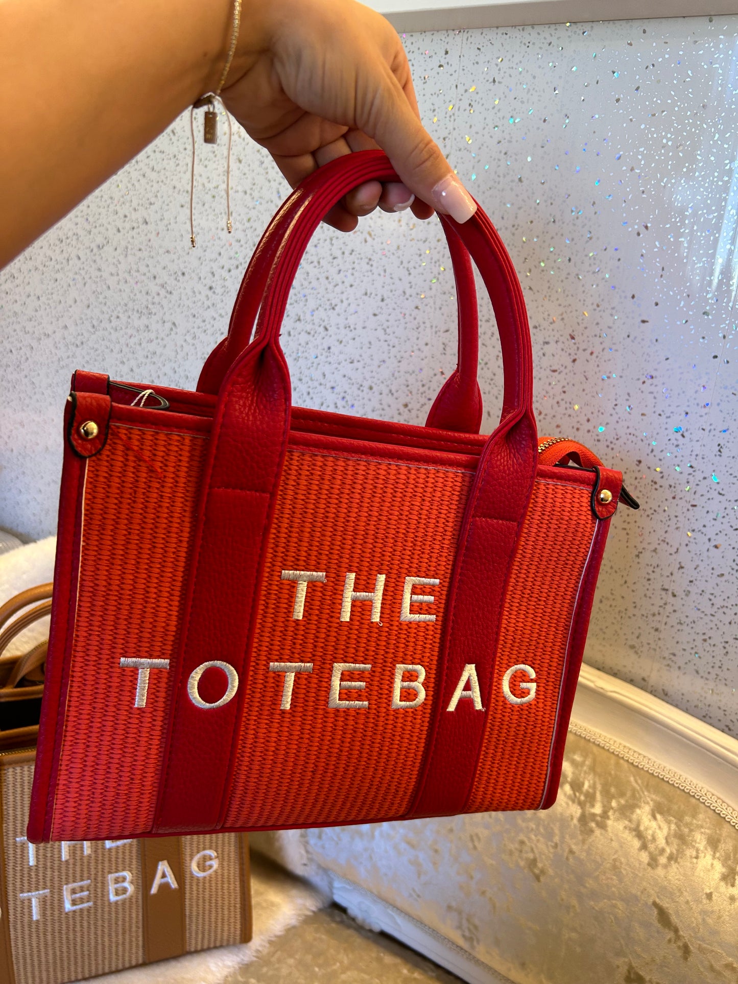 Red tote bag with 'THE TOTE BAG' text