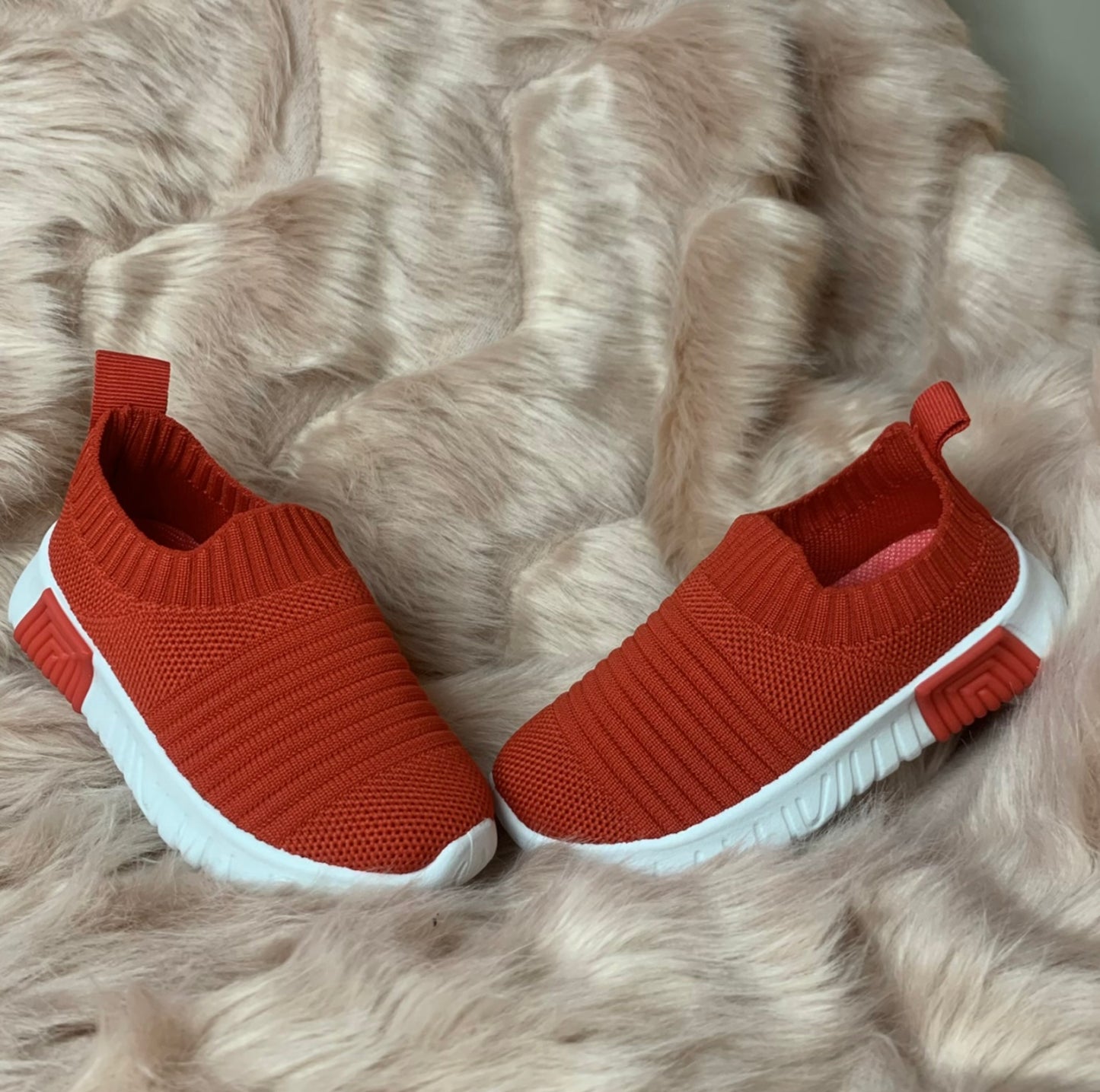 A pair of red kids' slip-on athletic shoes