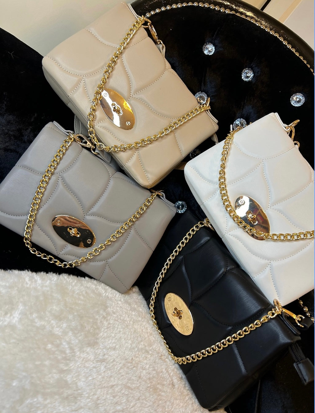 a collection of quilted handbag with a gold chain strap in white, beige, grey and black