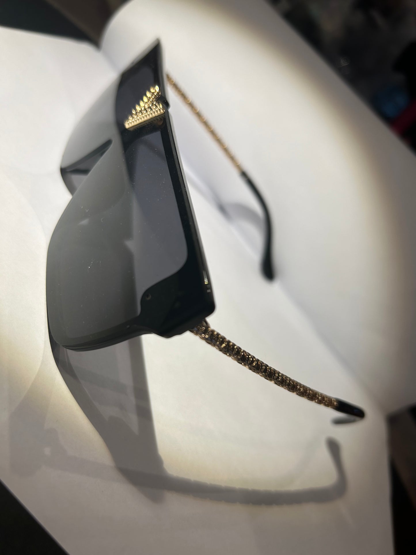 A pair of black sunglasses with gold detailing on the arms.
