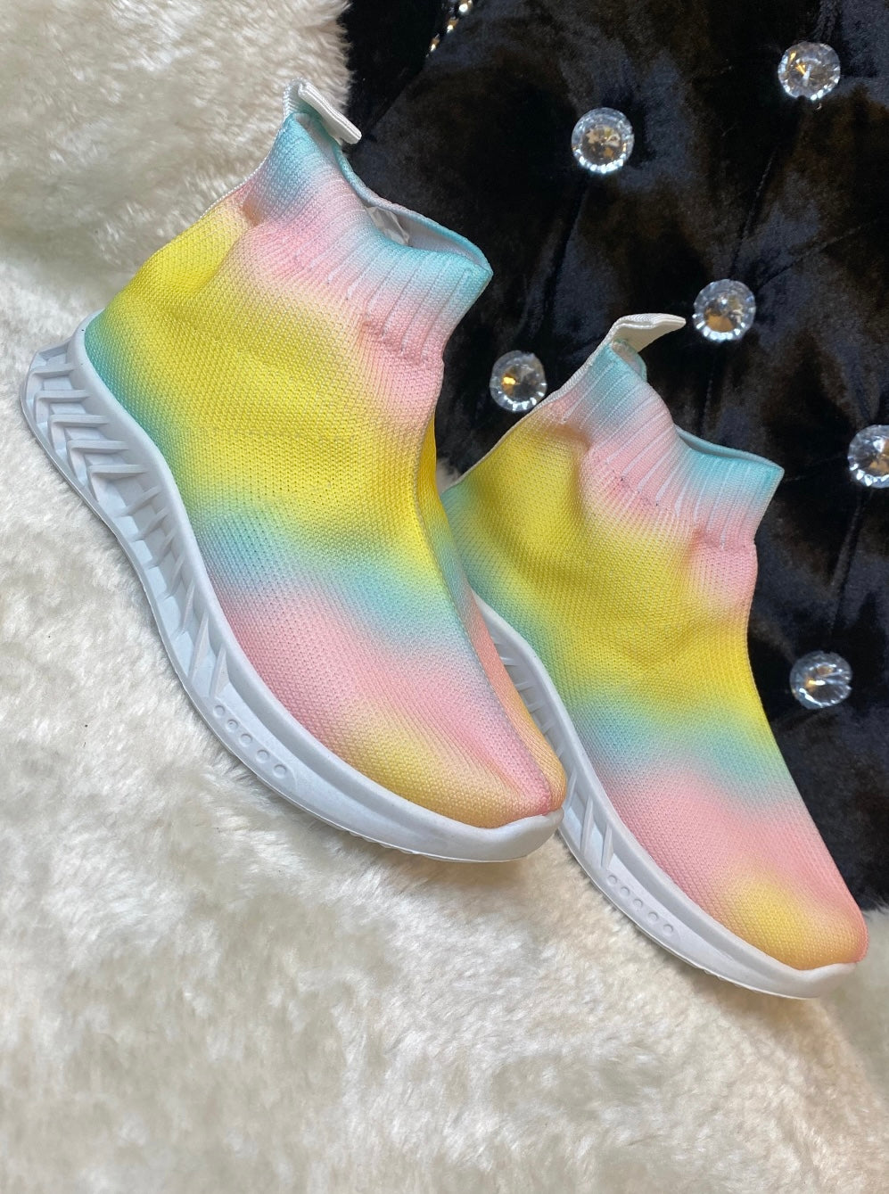 A pair of children's slip-on trainers with multicoloured upper parts and white sole