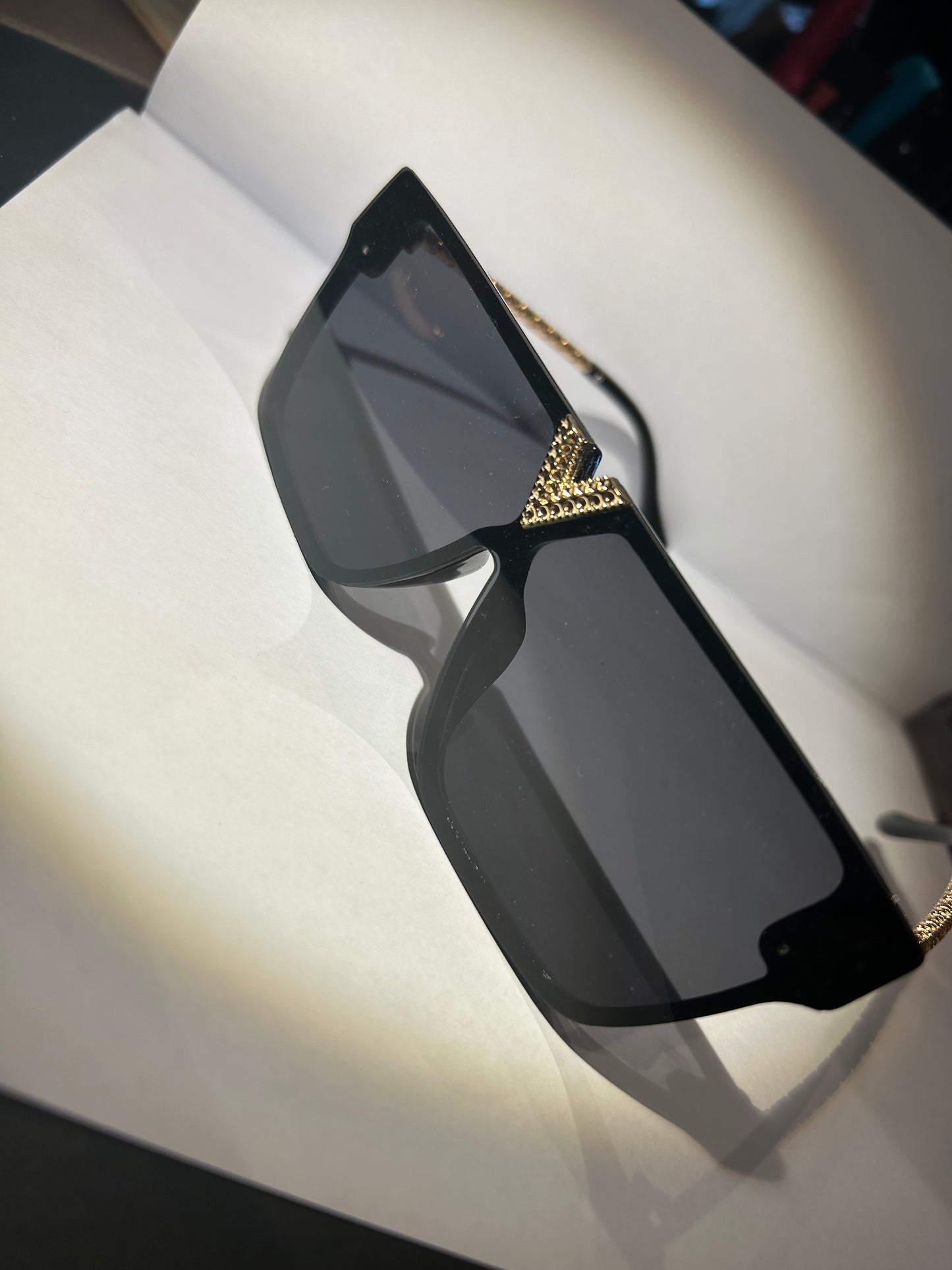 A pair of black sunglasses with gold detailing on the arms.