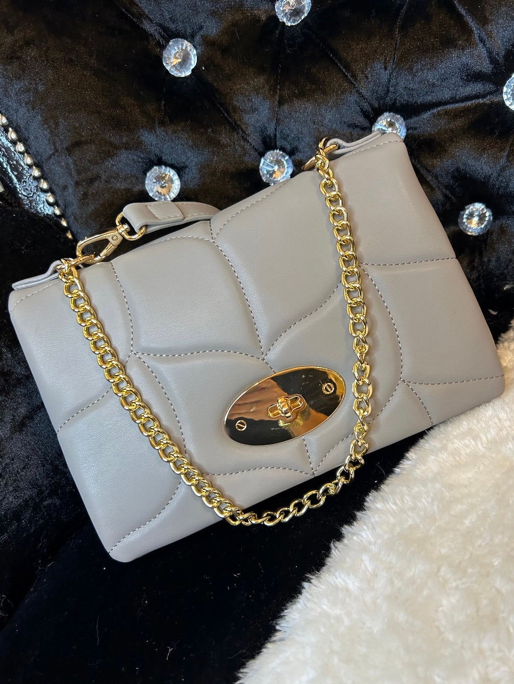 grey quilted handbag with a gold chain strap
