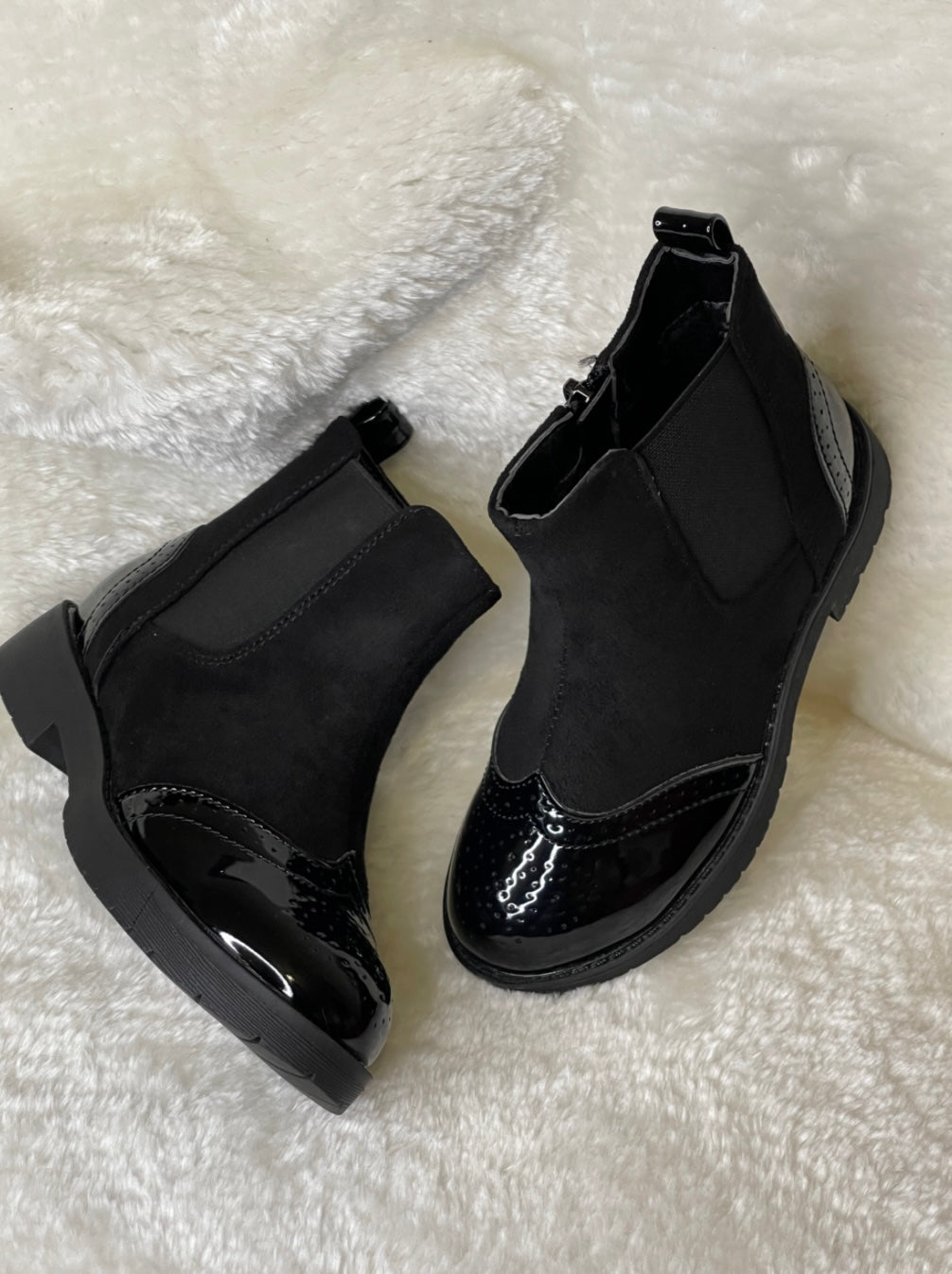 A pair of black ankle boots for girls with a glossy finish