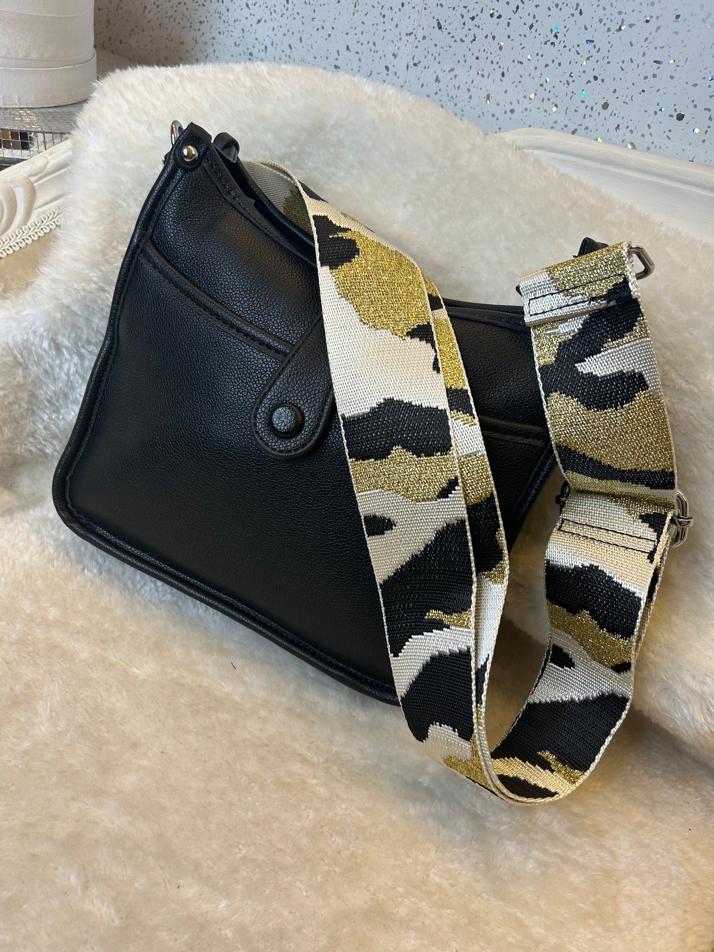 Black pouch with a camouflage-patterned strap on a textured surface