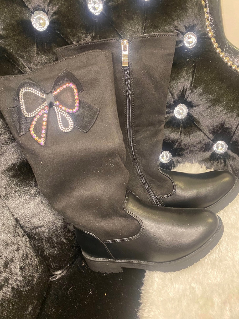 Knee high black boots with a crystal bow detail and zip-up fastening