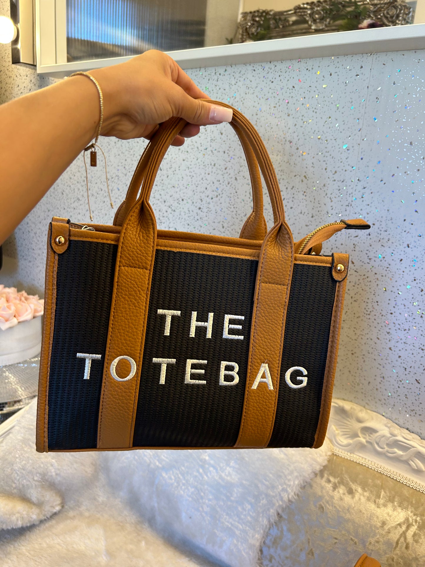 A black and brown tote bag with 'THE TOTE BAG' text