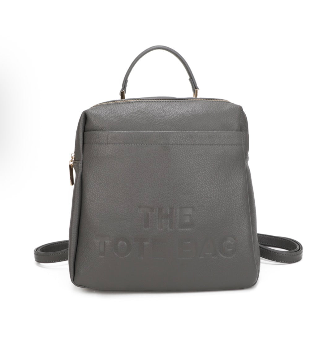 Grey rucksack with embossed “ the tote bag” writing on the front