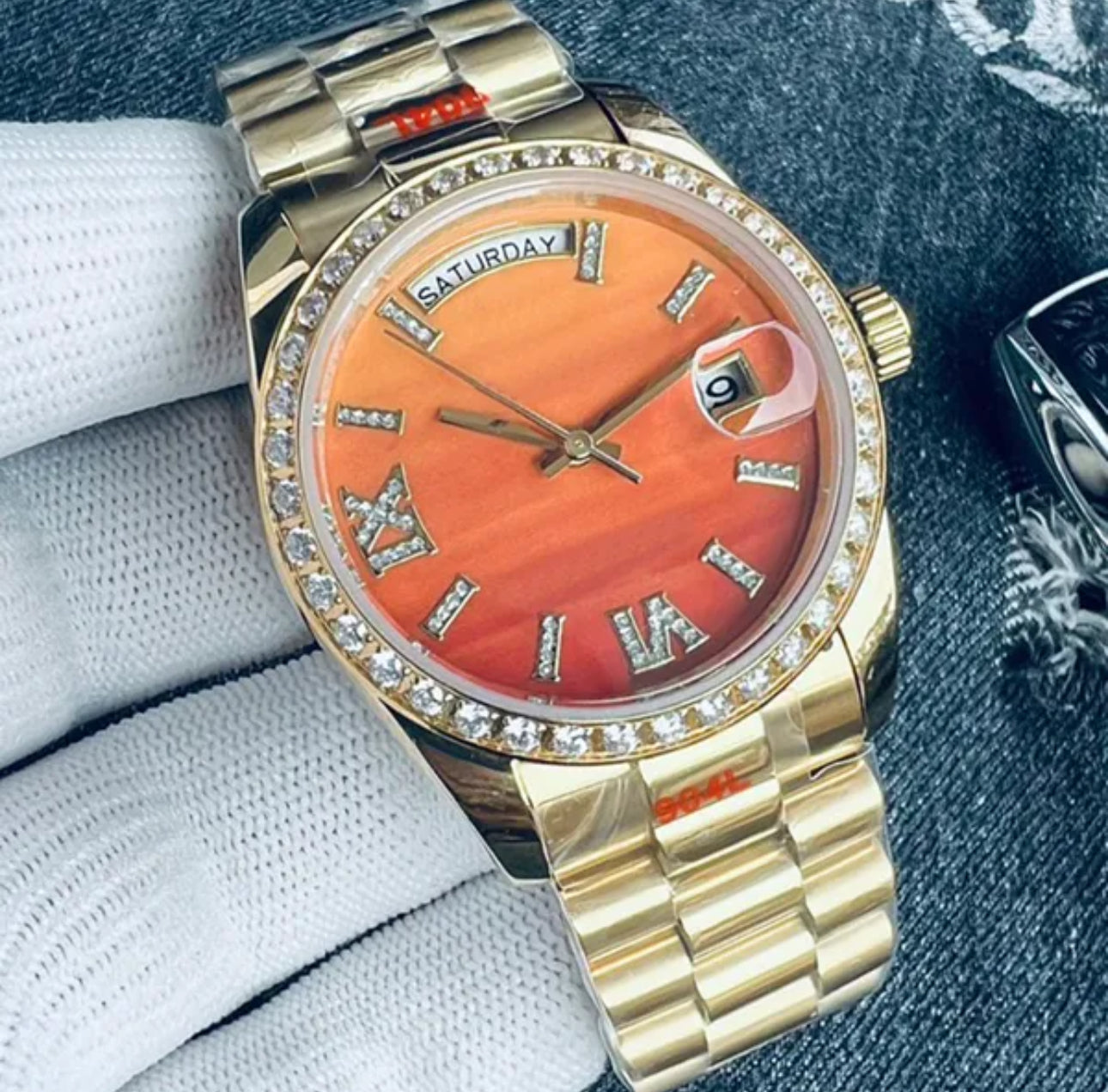 A gold-coloured watch with an orange dial and bling crystal rhinestones.