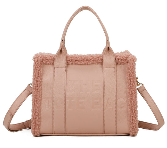 A pink mini tote handbag with debossed details and fuzzy edged trim, featuring an adjustable strap.