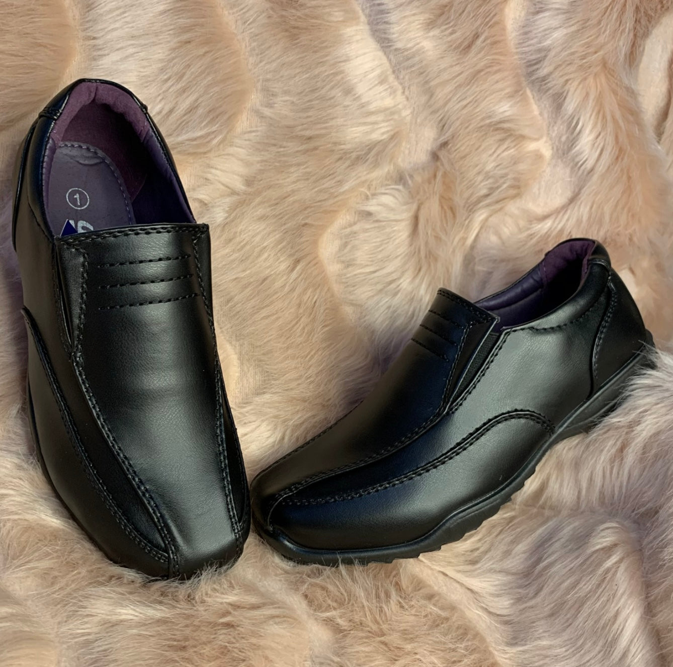 A pair of black slip-on boys' school shoes displayed