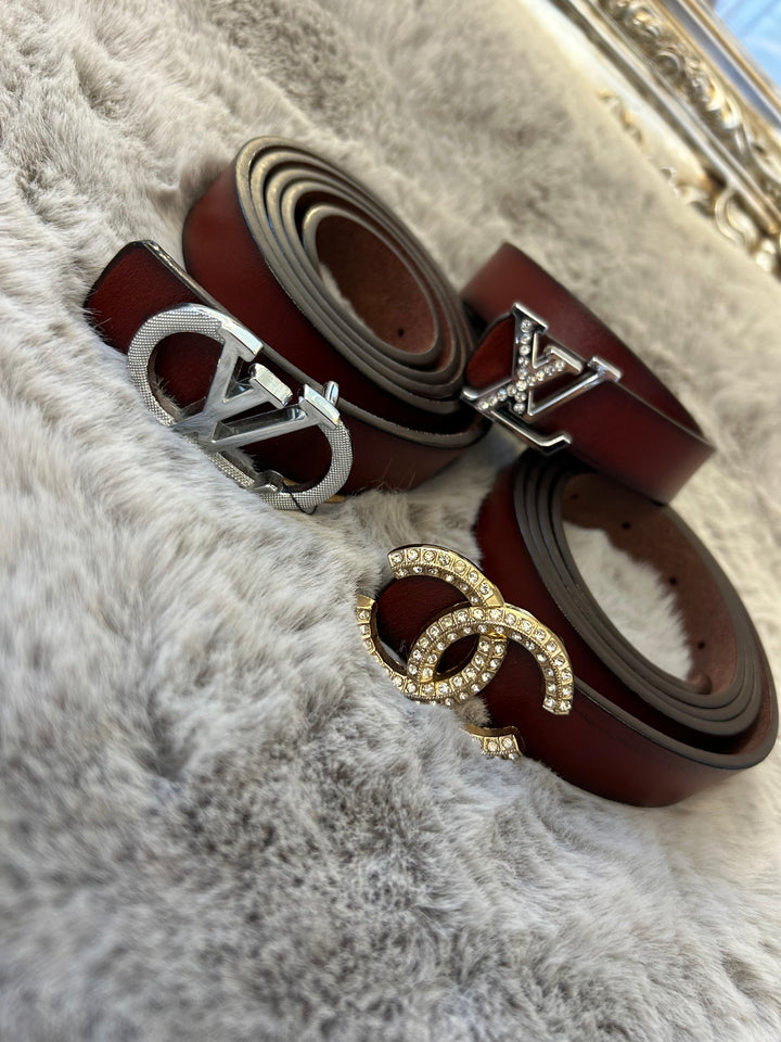 A collection of small brown belts with different buckles