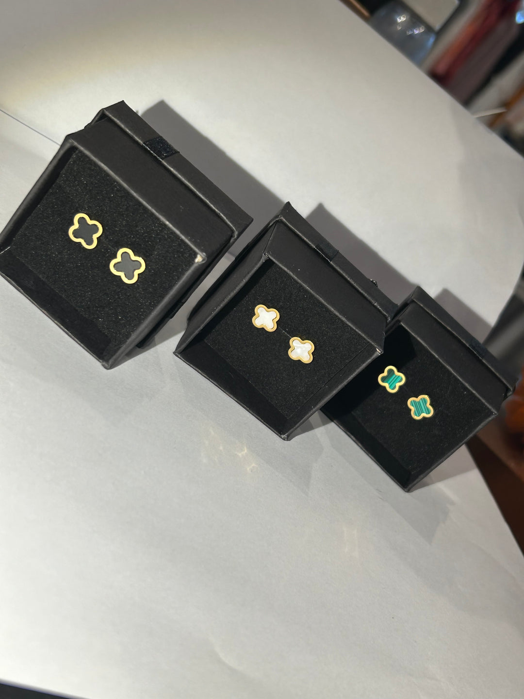 A pair of clover-shaped stud earrings in green and white and black