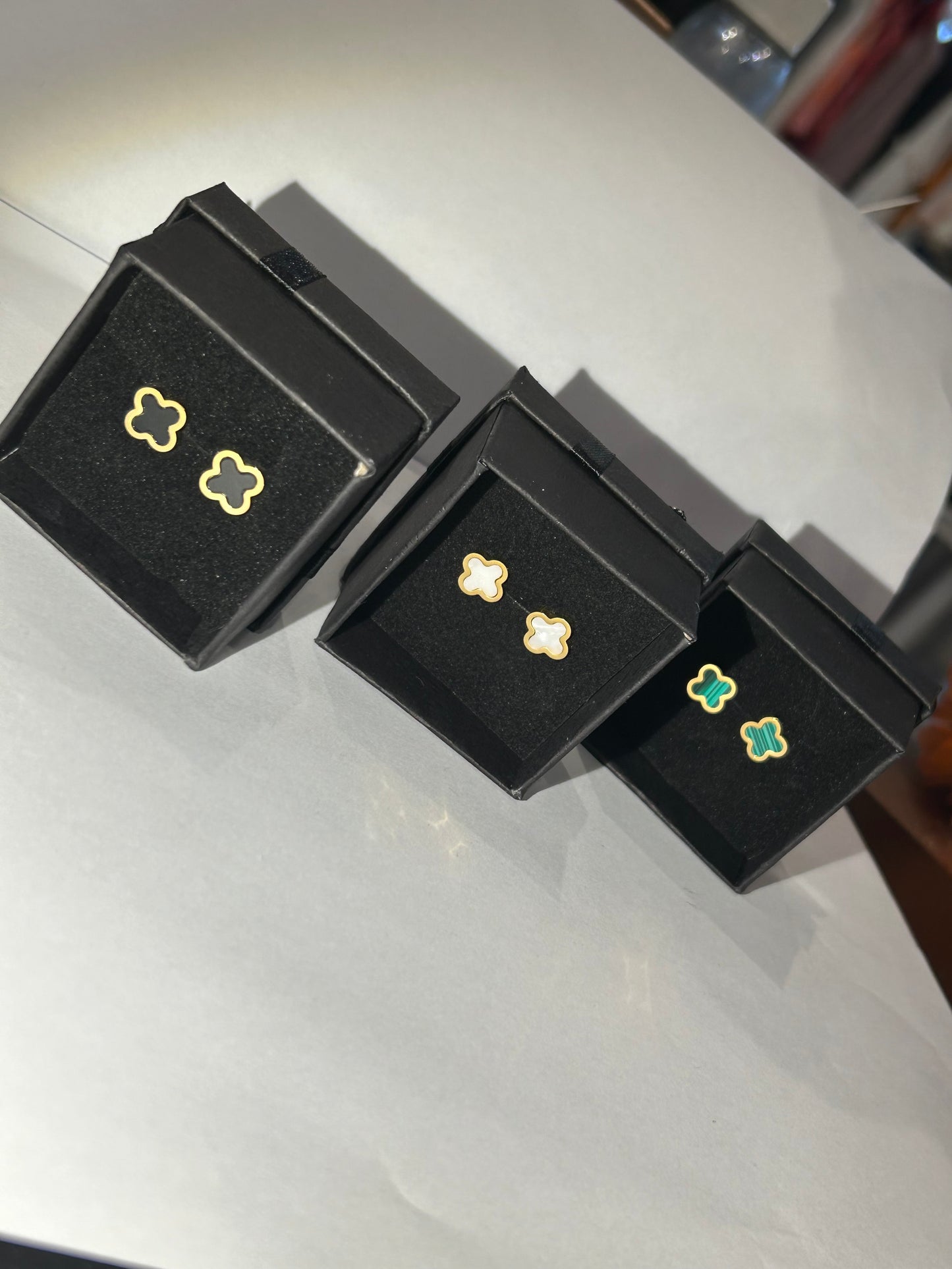 A pair of clover-shaped stud earrings in green and white and black