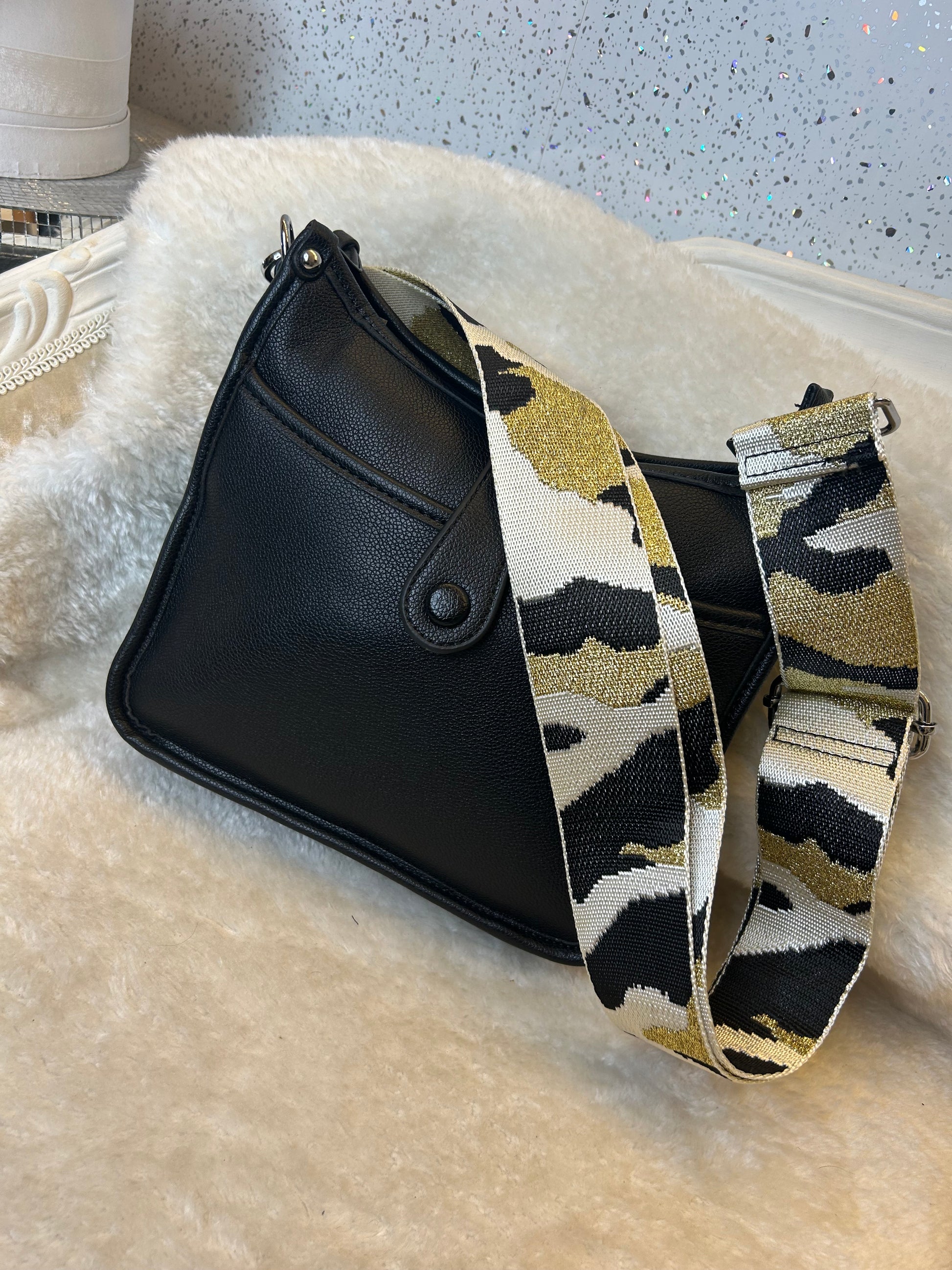Black bag with a patterned strap on a textured surface