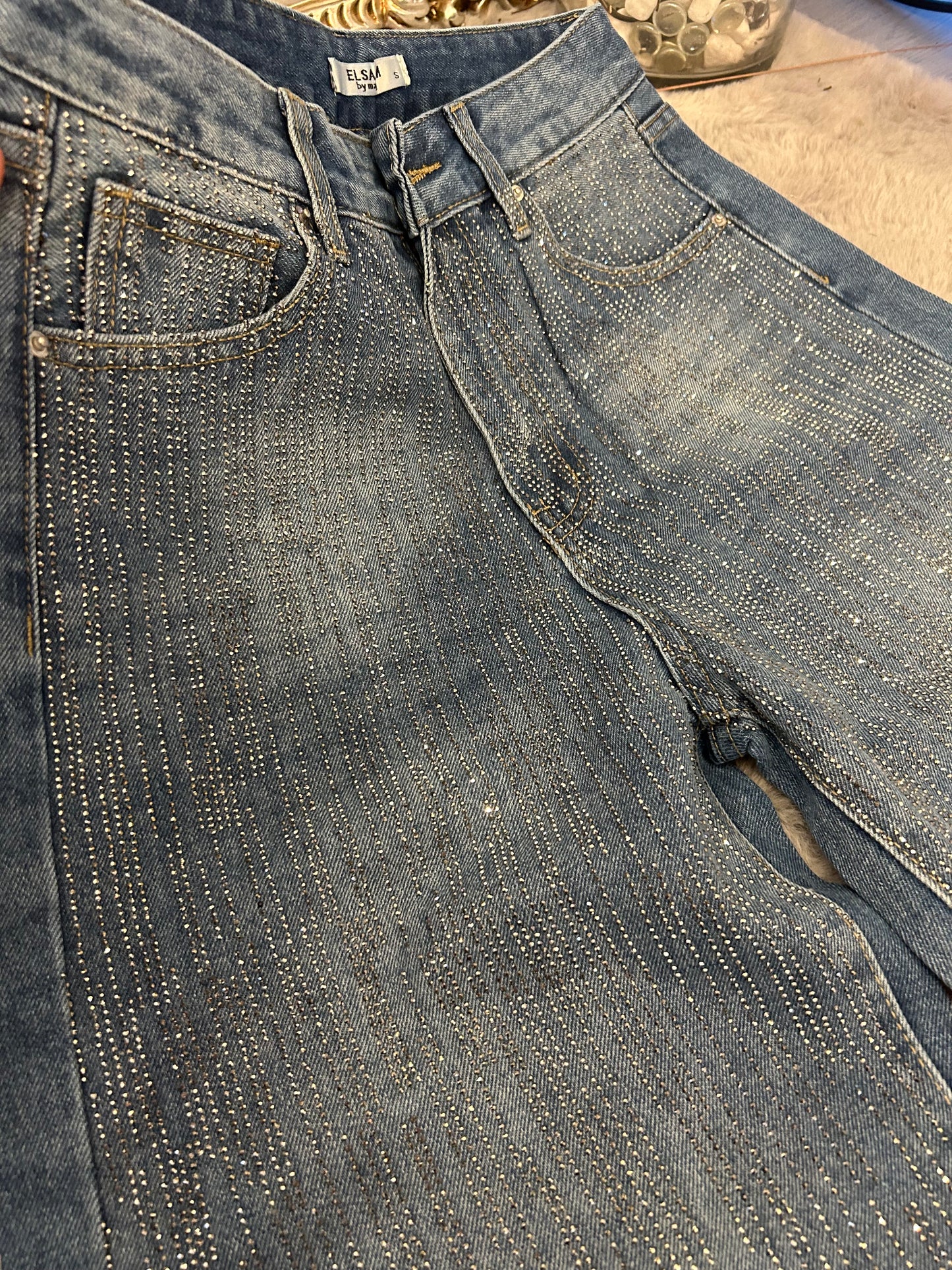 Close-up of a pair of blue jeans with crystals and texture.