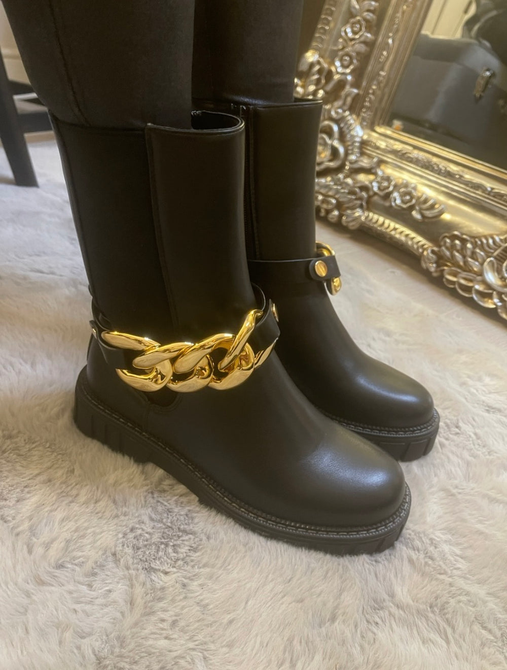 Black chunky ankle boots with gold chain detail worn on feet, stylish women’s boots
