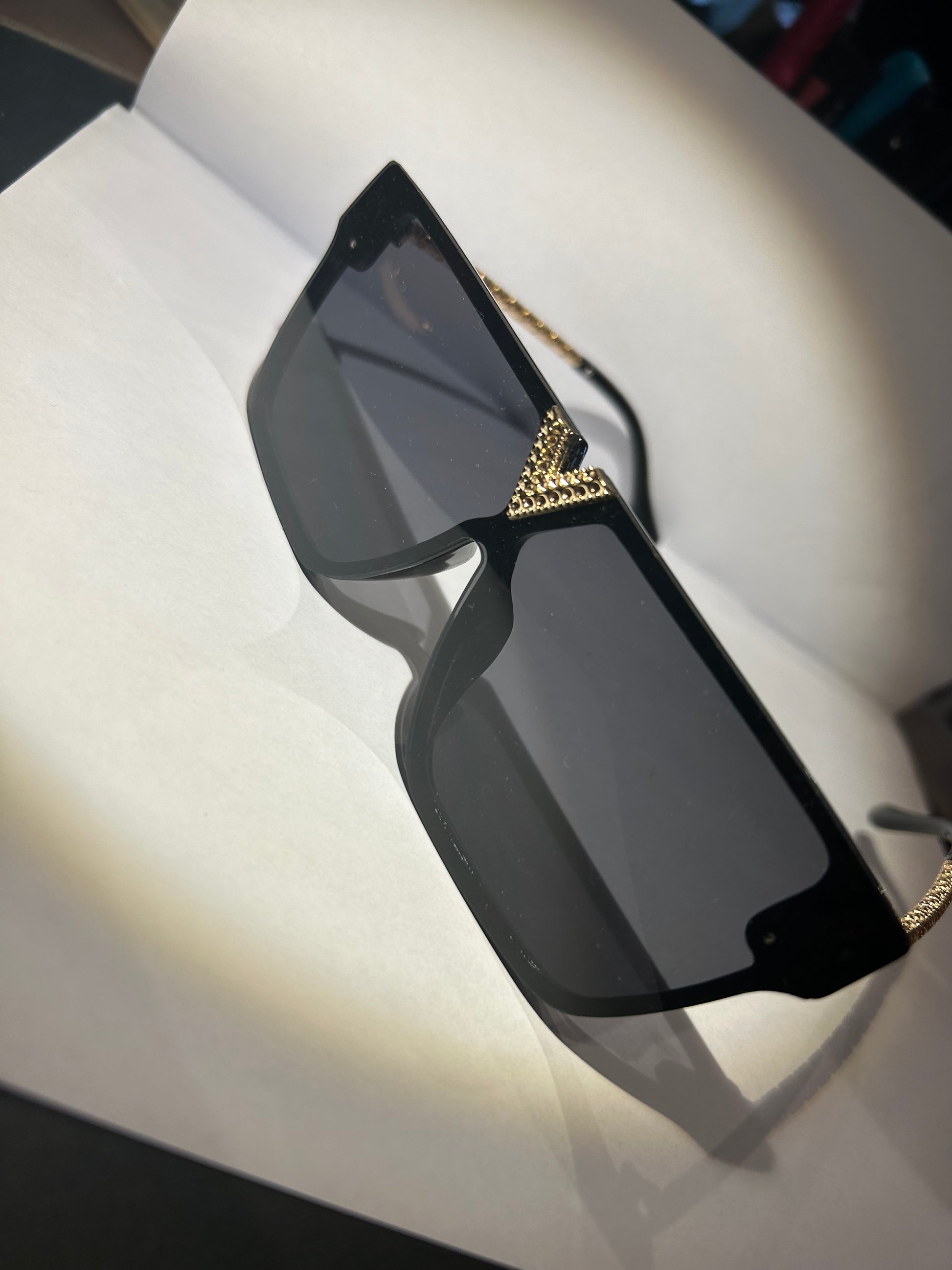 A pair of black sunglasses with gold detailing on the arms.