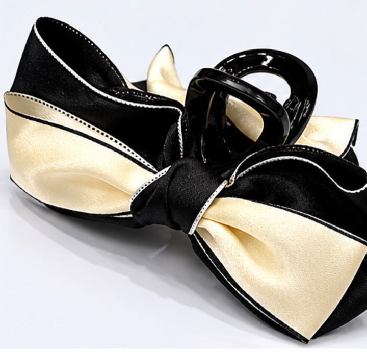 Black and cream satin bow hair clip with contrasting trim detail and glossy claw clip fastening