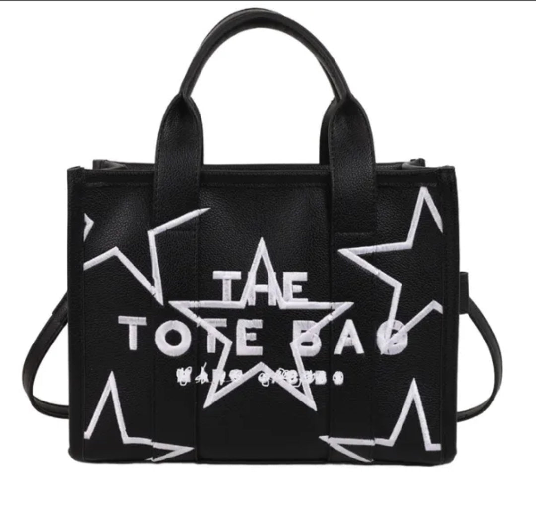 Black tote bag with white star designs and 'The Tote Bag' text on a white background