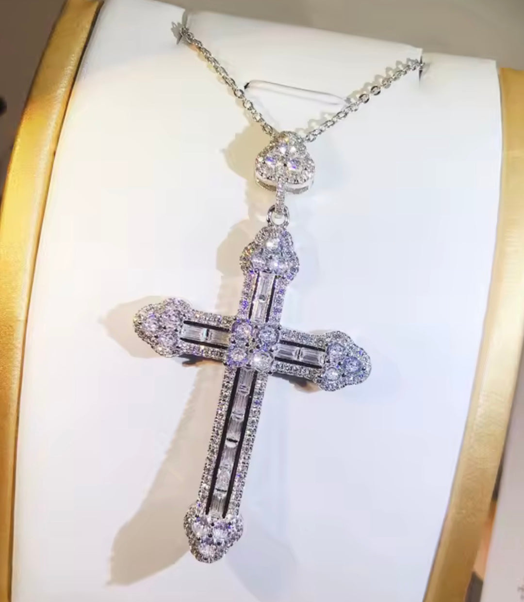 Diamond cross pendant on a white cushion with gold border