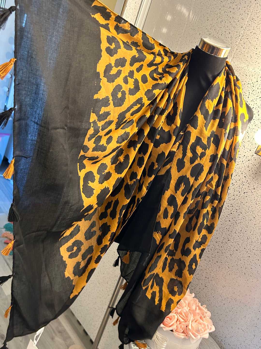 A leopard print tassel scarf, with the scarf predominantly in black and yellow tones.