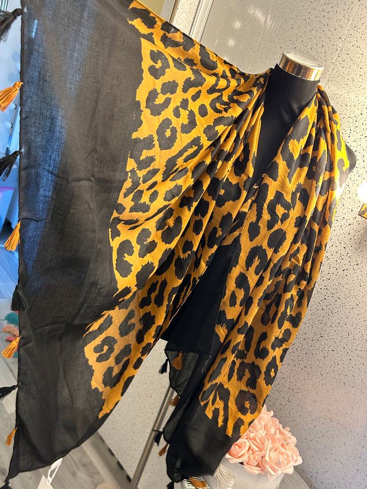 A leopard print tassel scarf, with the scarf predominantly in black and yellow tones.