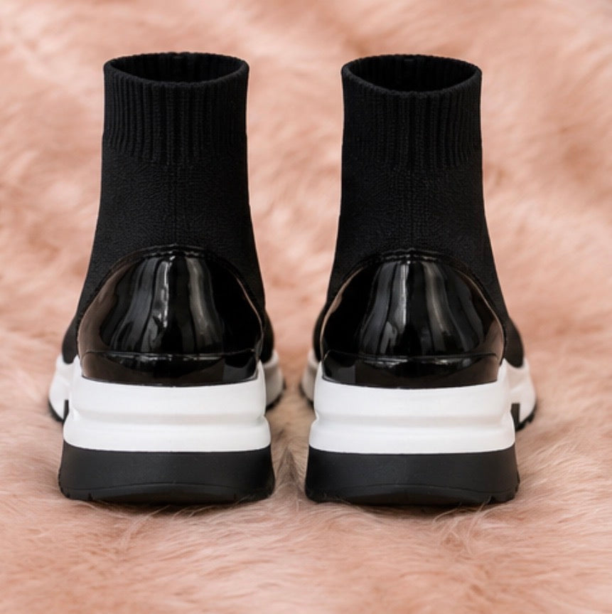 A pair of black and white slip-on trainers with a wedge sole.