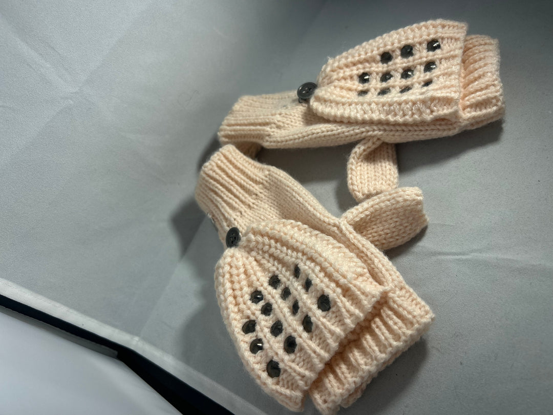 A pair of baby pink knitted mittens with stud patterns