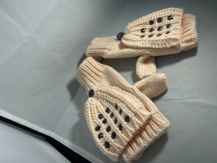 A pair of baby pink knitted mittens with stud patterns