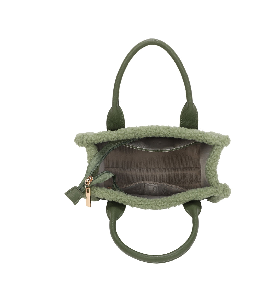 Inside view of green shearling trim tote bag showing beige fabric lining with slip pockets and zip closure.
