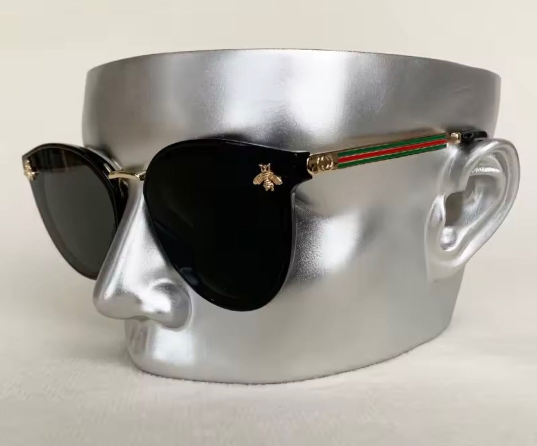 Black sunglasses with gold bee embellishment and green red stripe arms