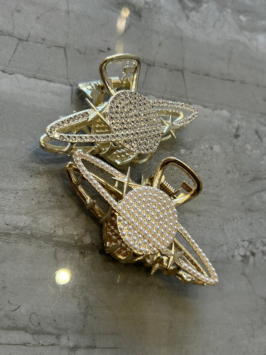Two gold-colored metal planet hair clips with crystal embellishments 