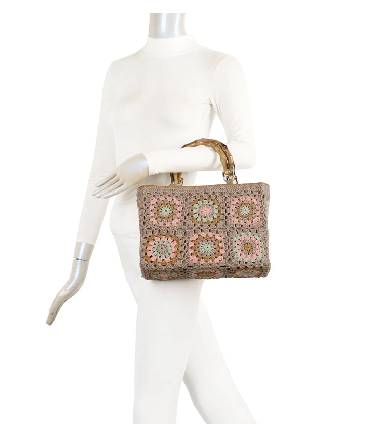 Beige crochet grab bags with bamboo handles and gold tone metal hardware.