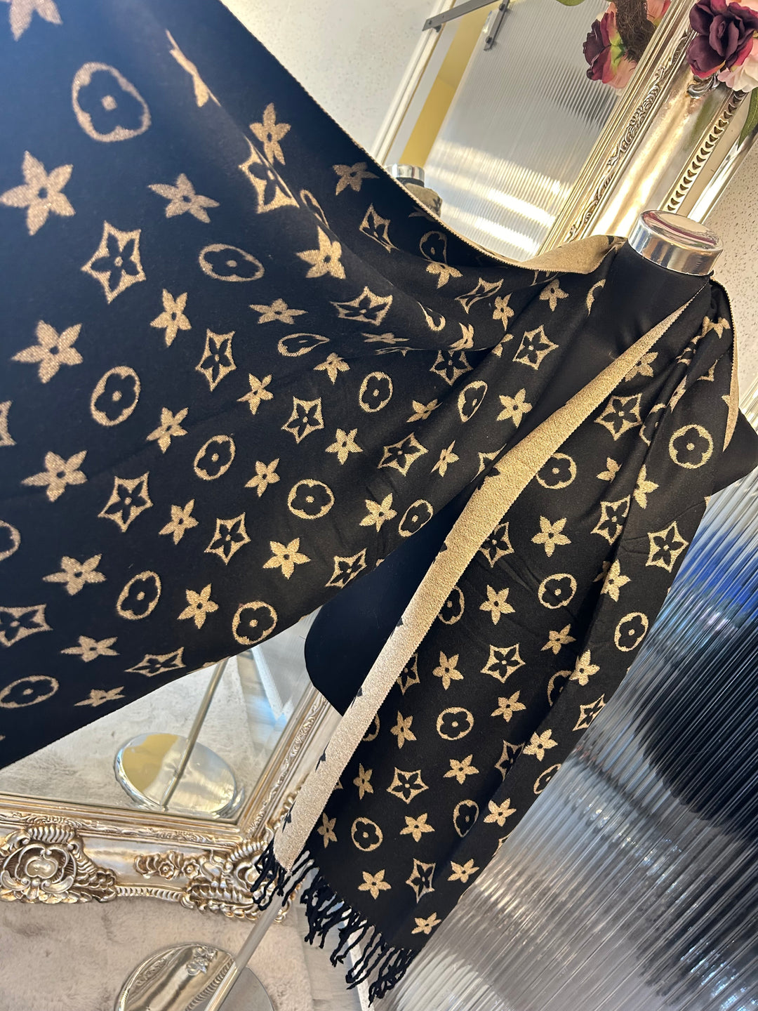 A black scarf with sparkly metalic thread floral patterns, draped elegantly with a focus on the sparkly details.