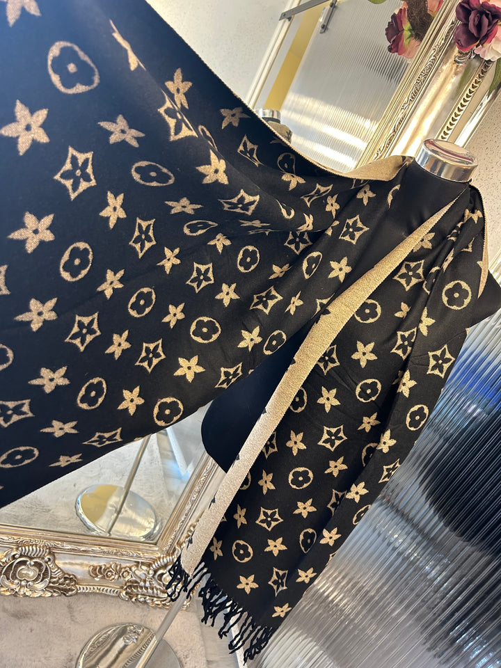 A black scarf with sparkly metalic thread floral patterns, draped elegantly with a focus on the sparkly details.