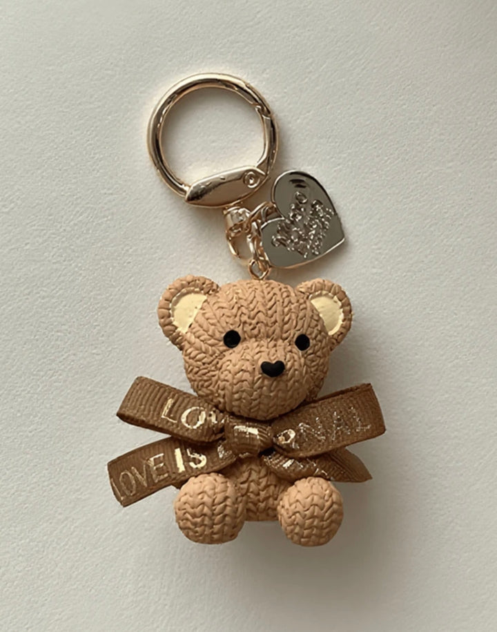     Beige teddy bear keyring charm with ribbon bow and gold heart pendant.