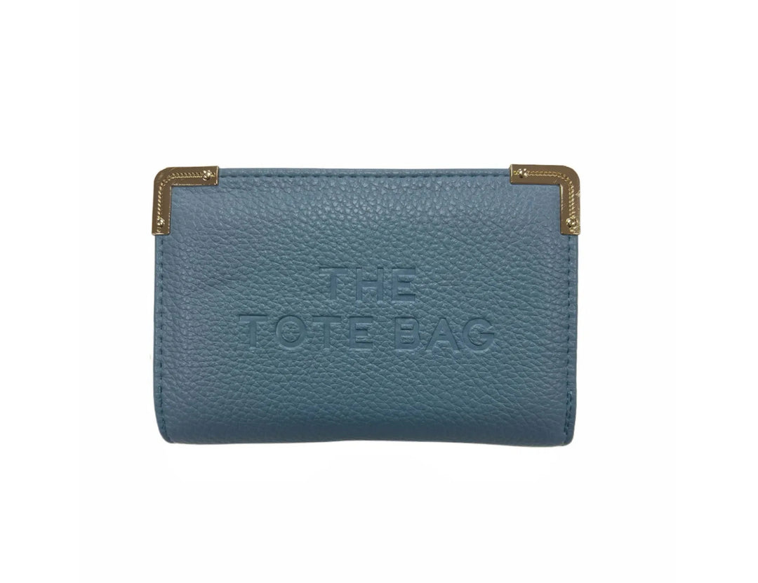 A blue synthetic tote bag with gold tone metal hardware, featuring a fold-over top with a closure, and the ‘THE TOTE BAG&
