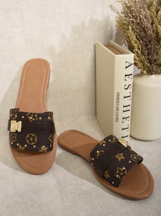 Brown monogram buckle sliders with gold detail displayed on neutral background