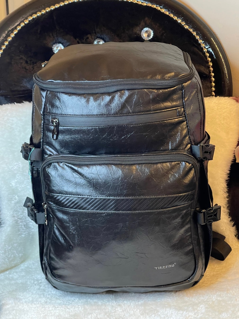 large black leather-look backpack with multiple zip compartments, adjustable straps and modern design, practical travel and work bag