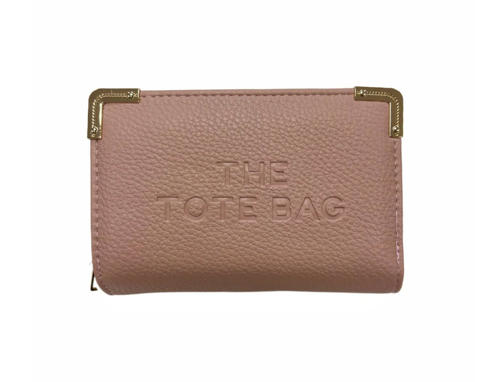 A pink synthetic tote bag with gold tone metal hardware, featuring a fold-over top with a closure, and the ‘THE TOTE BAG' embossed on the front.