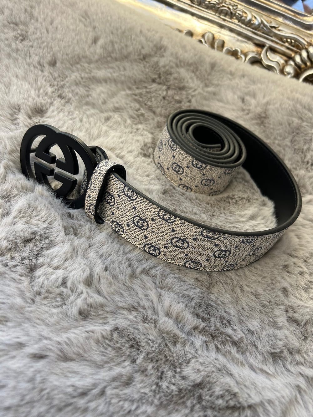 A coiled grey and black belt with a patterned buckle