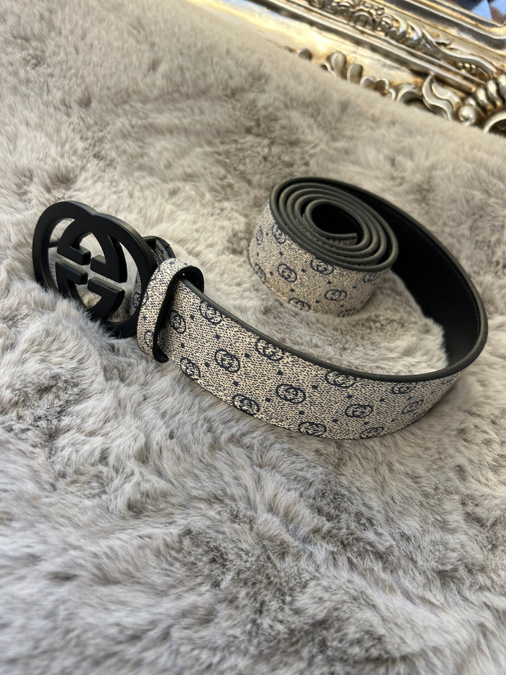 A coiled grey and black belt with a patterned buckle