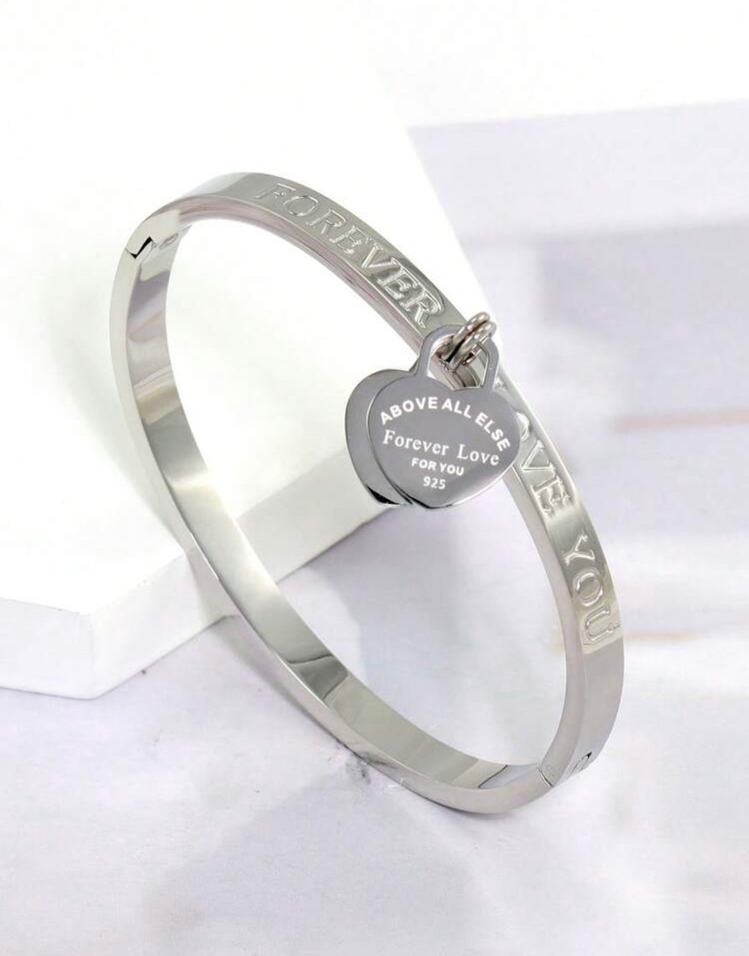 Silver three-piece stainless steel love bangle bracelet set with heart charms and crystal detailing.