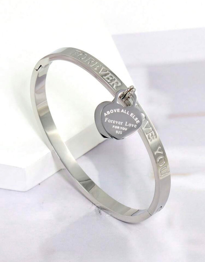 Silver three-piece stainless steel love bangle bracelet set with heart charms and crystal detailing.