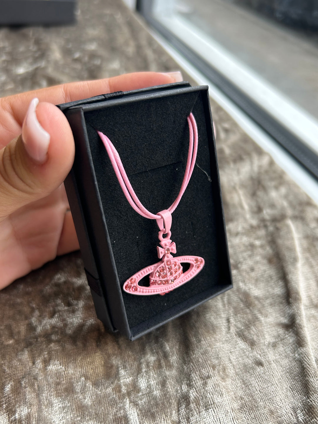 A pink rope necklace with a planet-shaped crystal pendant